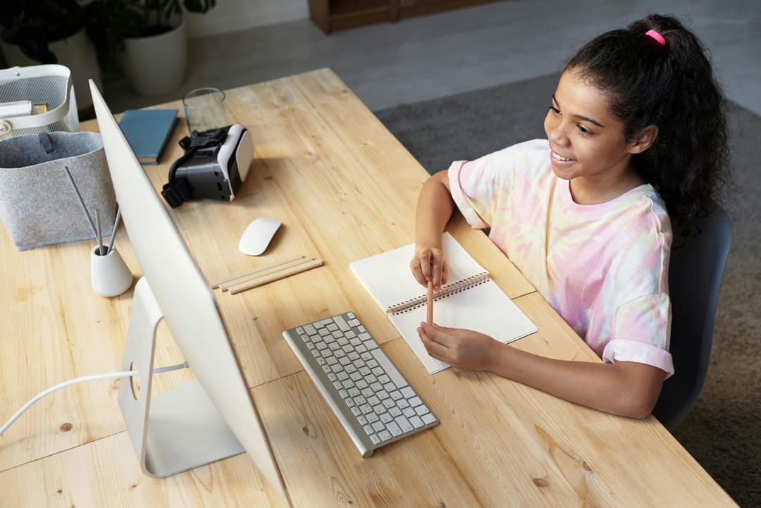 Student engaged in an online lesson with notebook and computer